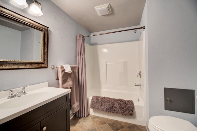 bathroom featuring visible vents, toilet, shower / bath combo, a textured wall, and vanity