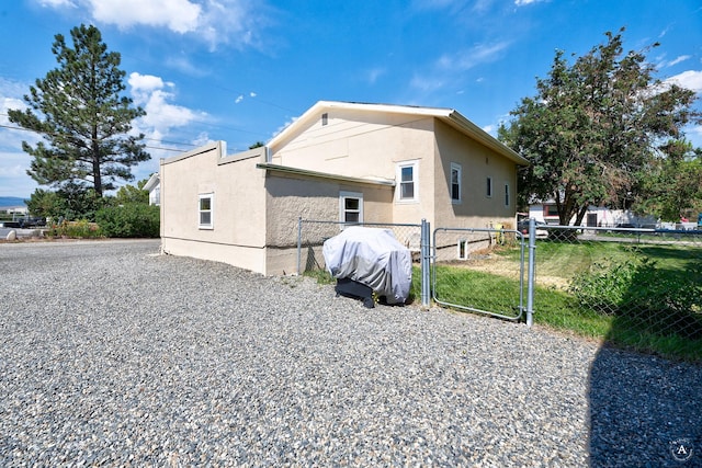 view of side of home with a gate, stucco siding, and fence