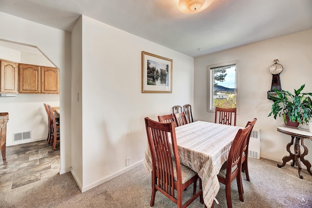 dining room with radiator heating unit, baseboards, visible vents, and light carpet