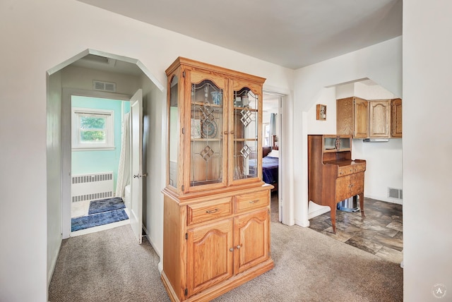 corridor featuring radiator, arched walkways, visible vents, and carpet floors