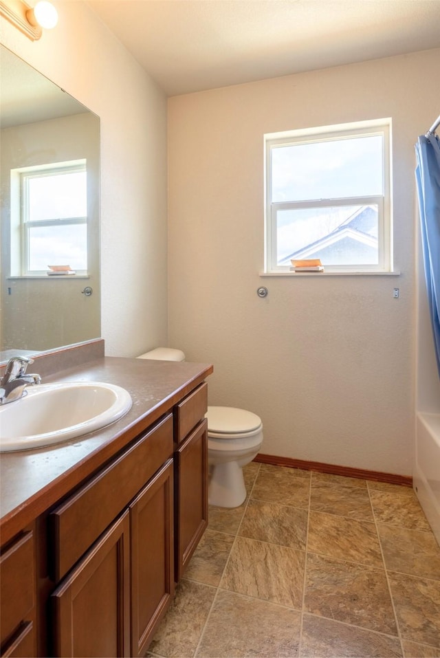 bathroom with vanity, curtained shower, toilet, and baseboards