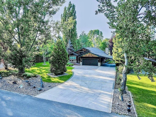 view of front of property with a front yard, stone siding, a garage, and driveway