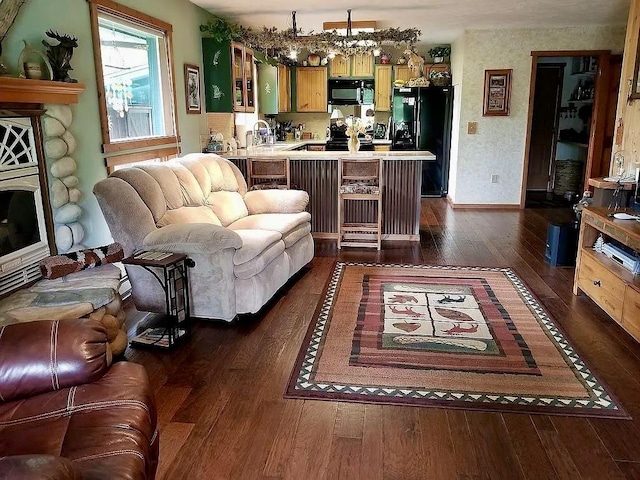 living area featuring wallpapered walls, dark wood finished floors, and baseboards