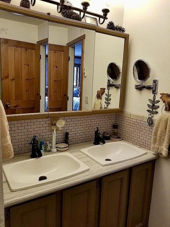 full bathroom featuring a sink, backsplash, and double vanity