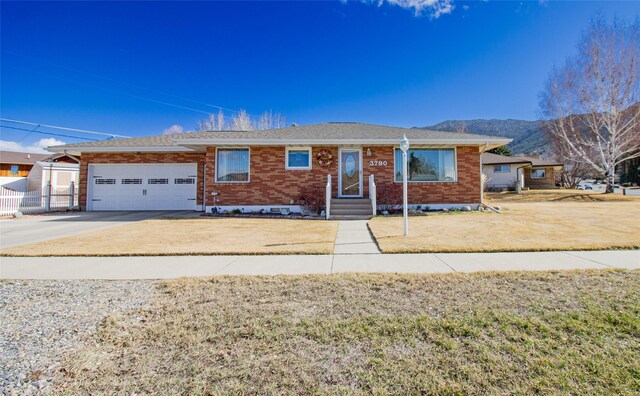 3790 Continental Dr, Butte, MT 59701 - ranch-style home featuring driveway, a front yard, a mountain view, brick siding, and a garage