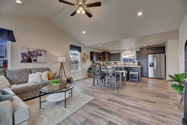 living area featuring baseboards, high vaulted ceiling, recessed lighting, ceiling fan, and light wood-type flooring