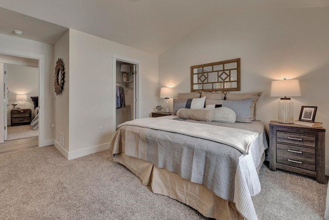 bedroom featuring a spacious closet, baseboards, lofted ceiling, carpet floors, and a closet