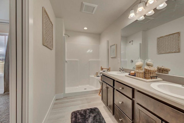 bathroom featuring a sink, double vanity, visible vents, and a stall shower