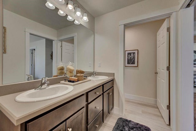 full bathroom featuring double vanity, wood finished floors, baseboards, and a sink