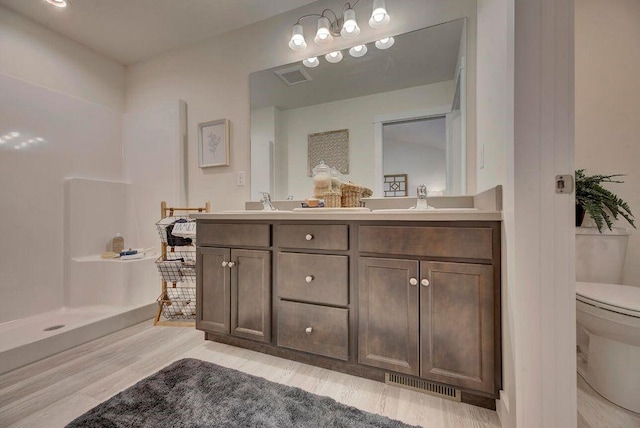 bathroom with double vanity, toilet, visible vents, and a sink