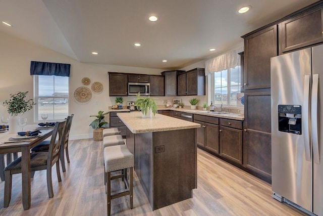 kitchen featuring a kitchen island, dark brown cabinets, stainless steel appliances, and light wood-style flooring