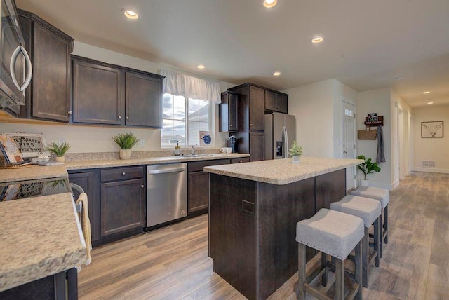 kitchen featuring visible vents, a breakfast bar area, light wood-type flooring, light countertops, and stainless steel appliances