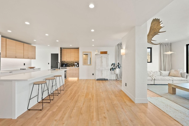 kitchen featuring modern cabinets, light brown cabinetry, tasteful backsplash, open floor plan, and light wood-style floors