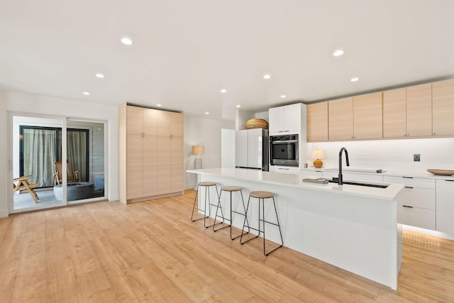 kitchen with light countertops, light wood-style floors, freestanding refrigerator, and a sink