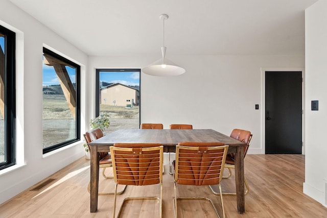 dining area featuring visible vents, baseboards, and light wood finished floors