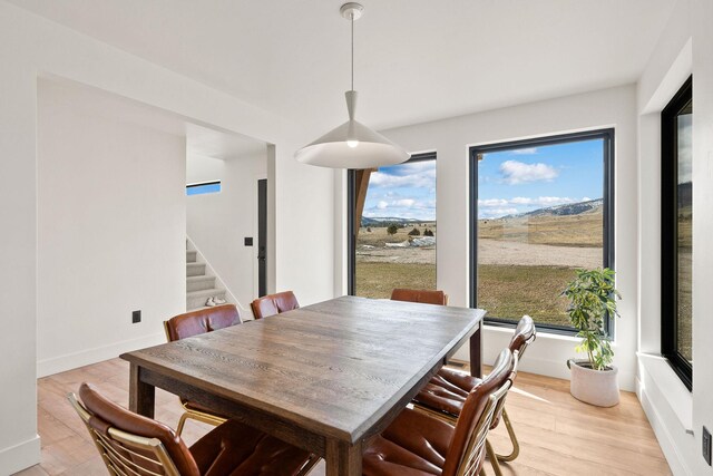 dining area featuring baseboards, stairs, and light wood-style floors