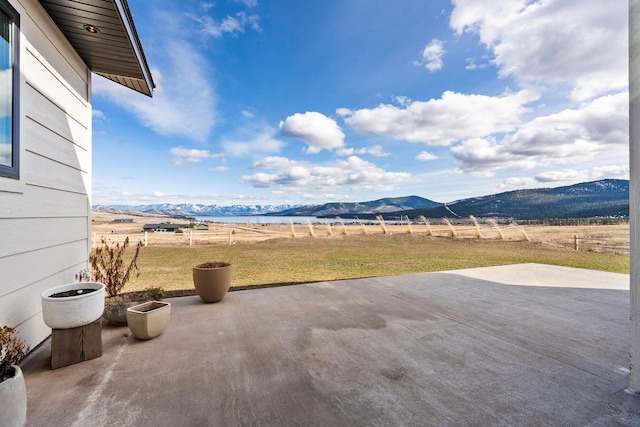 view of patio / terrace with a rural view, a mountain view, and fence