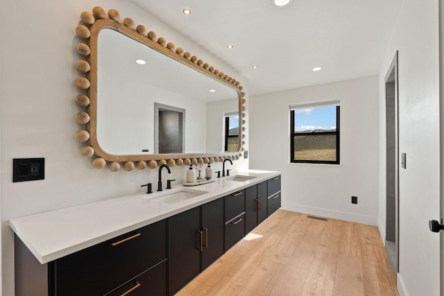 full bathroom with double vanity, recessed lighting, wood finished floors, and a sink