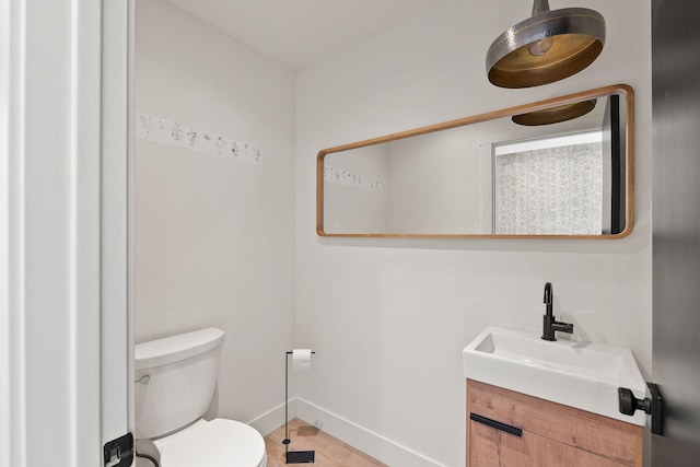 bathroom with toilet, vanity, and baseboards