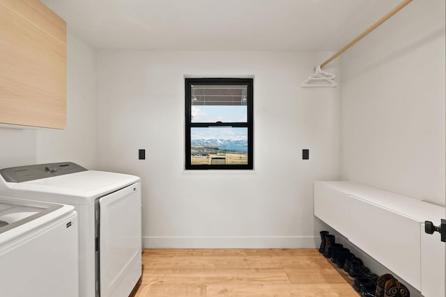 clothes washing area with light wood-type flooring, baseboards, separate washer and dryer, and laundry area