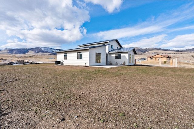 back of house featuring cooling unit, a lawn, a mountain view, and a patio area