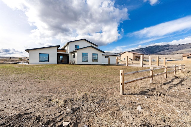 rear view of property featuring a lawn and fence