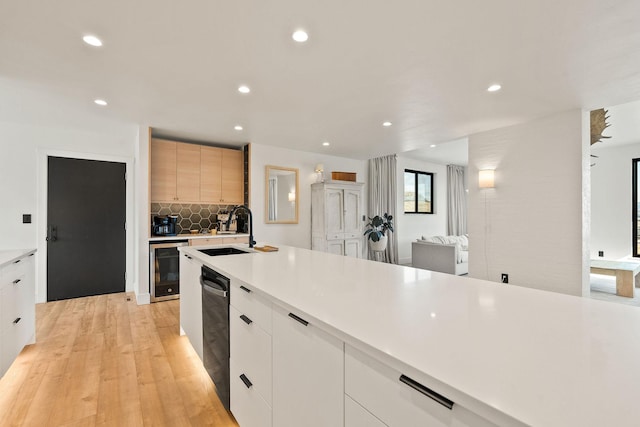 kitchen with a sink, light countertops, wine cooler, dishwasher, and modern cabinets