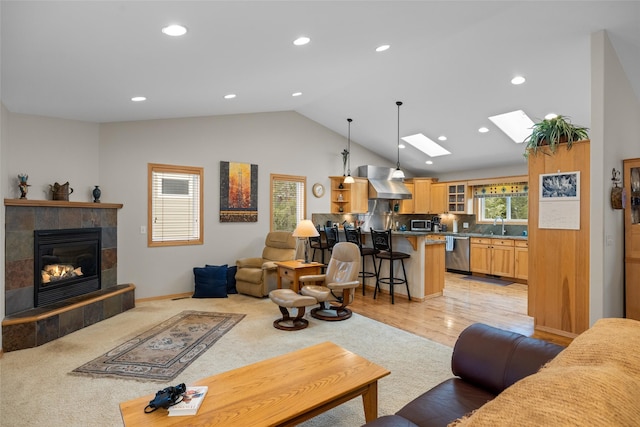 living area featuring lofted ceiling with skylight, plenty of natural light, recessed lighting, and a tile fireplace