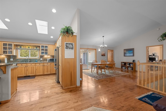 kitchen featuring light wood-style floors, glass insert cabinets, an inviting chandelier, and a sink