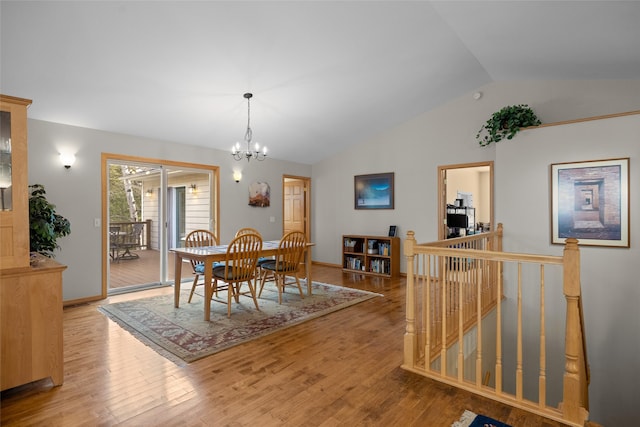 dining room with baseboards, an inviting chandelier, wood finished floors, and vaulted ceiling