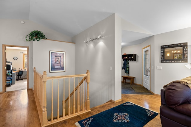 corridor featuring baseboards, an upstairs landing, wood finished floors, and vaulted ceiling