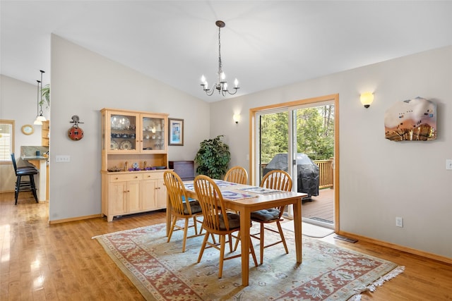 dining area featuring vaulted ceiling, a notable chandelier, baseboards, and light wood-type flooring