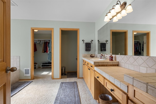 full bathroom with a walk in closet, visible vents, backsplash, baseboards, and vanity