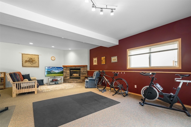 workout room with baseboards, carpet, and a stone fireplace