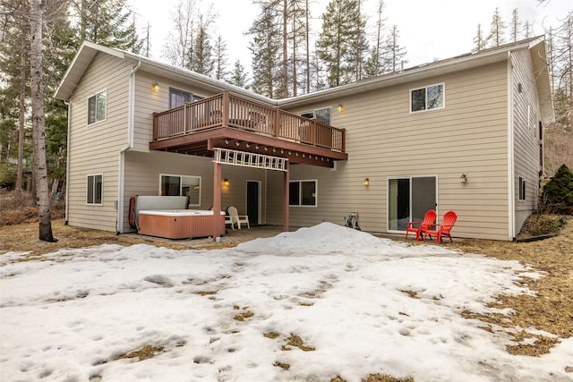 snow covered house featuring a hot tub and a deck