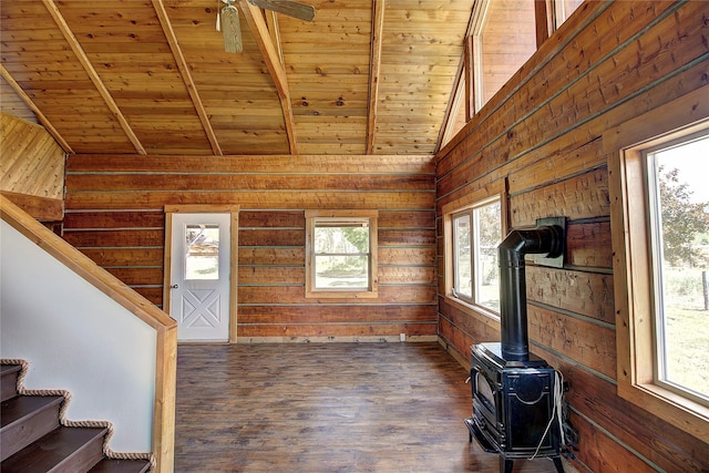 interior space featuring wooden walls, dark wood finished floors, beamed ceiling, stairs, and wooden ceiling