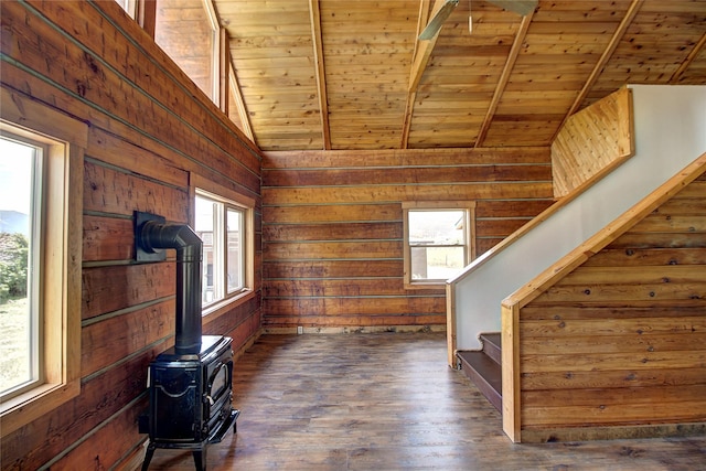 living area with stairs, wooden ceiling, a wood stove, and wood walls