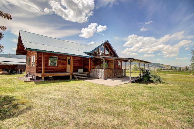 back of house with a yard, a patio, a carport, and metal roof