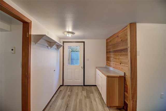 doorway to outside with light wood-style flooring, baseboards, and a textured ceiling