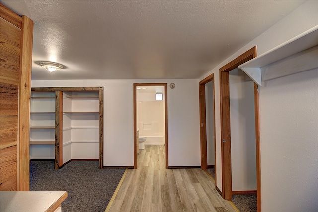 interior space featuring light wood-style flooring, baseboards, a closet, and a textured ceiling