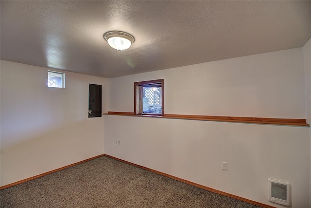 below grade area featuring visible vents, baseboards, carpet floors, electric panel, and a textured ceiling