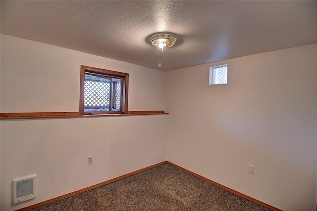 carpeted empty room with visible vents, baseboards, a textured ceiling, and a healthy amount of sunlight