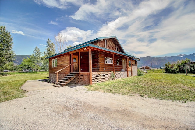 log home featuring a porch, a mountain view, and a front lawn