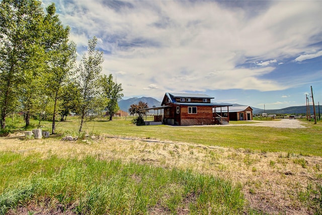 view of yard with a carport, a mountain view, and dirt driveway