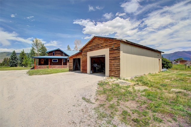 view of front of property with gravel driveway, an outdoor structure, an attached garage, and a mountain view