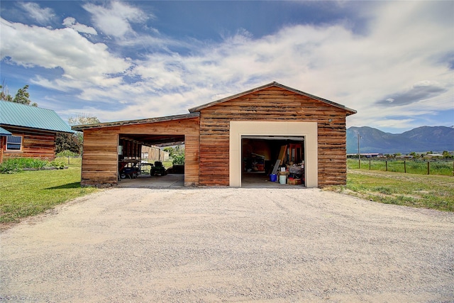 garage with gravel driveway, a mountain view, fence, and a garage