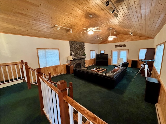 rec room featuring a stone fireplace, vaulted ceiling, rail lighting, wooden ceiling, and carpet flooring