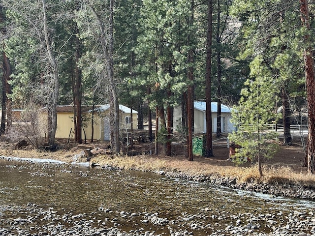 exterior space with a view of trees, a water view, and fence