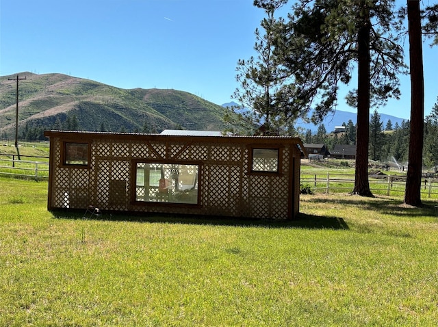 exterior space with a rural view, a lawn, a mountain view, and fence