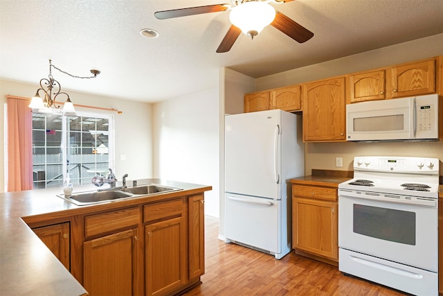 kitchen with white appliances, light wood-style flooring, ceiling fan, hanging light fixtures, and a sink